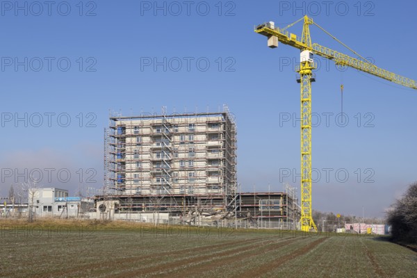 Unfinished building with yellow construction crane, construction site under blue sky, housing construction, new construction of 50 flats, new development area, apartment building, construction site, Winnenden, Baden-Württemberg, Germany, Europe
