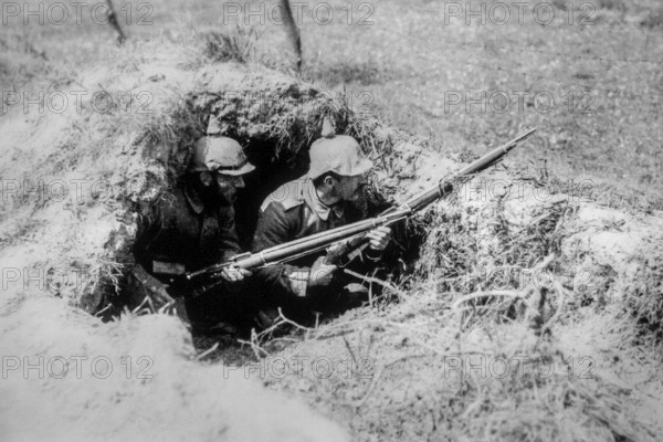 Two 1916 WWI German Landsturm soldiers with Pickelhaube, spiked helmets in foxhole, dugout on World War One battlefield in northern France