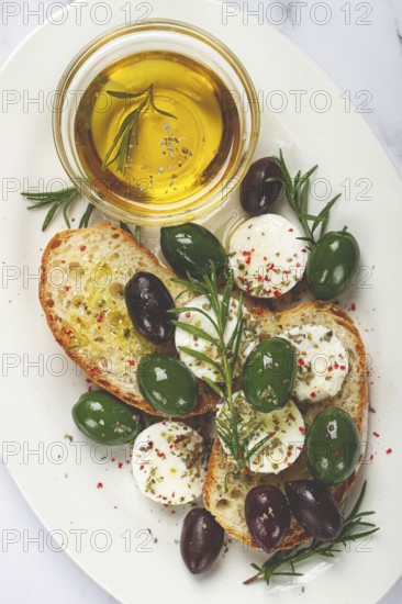 A plate with a snack, ciabatta bread with cheese and olives, olive oil, spices and herbs, top view, no people