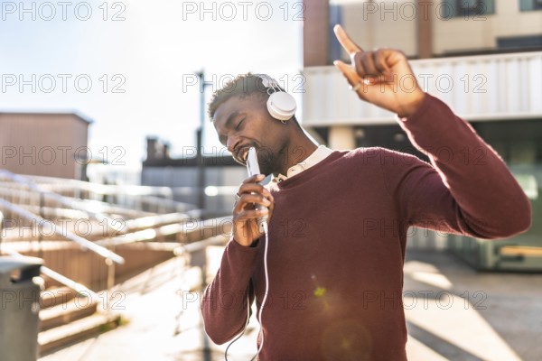 African man dancing listening to music with headphones in the city in a sunny day of autumn