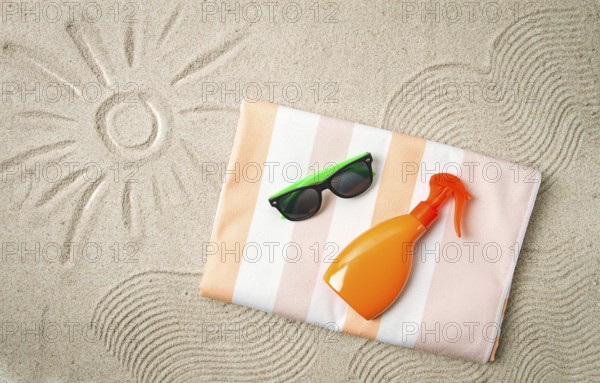 Drawing on the sand, sun and waves, sunglasses, with an orange bottle, beach towel, sun spray, on the sand, top view, no people