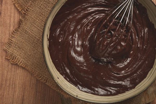 A bowl of chocolate dough, a whisk for whipping, baking, structure and consistency, homemade, top view, no people