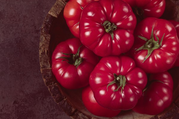 Pink tomatoes, in a rustic wooden bowl, close-up, no people