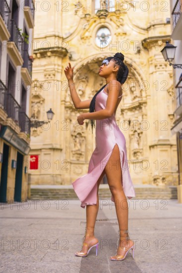 Beautiful Dominican ethnic girl with braids with a beautiful pink dress. Fashion enjoying summer in a beautiful city church, vertical photo