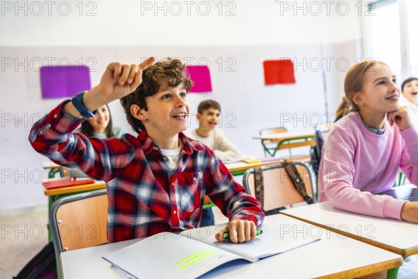 Elementary school student raising hand to answer a question during class, showing eagerness to learn and participate in the classroom environment
