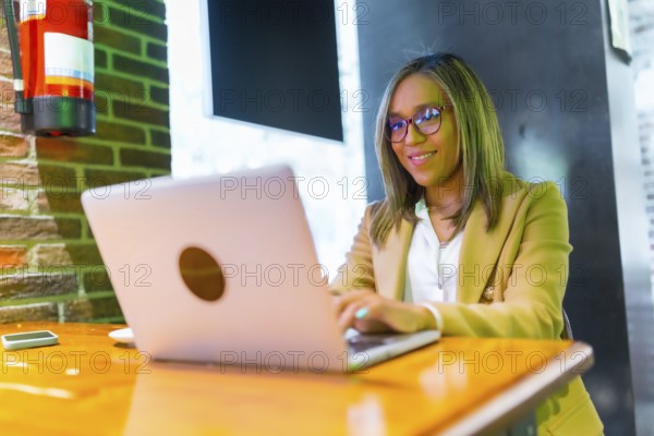 Happy beauty latin businesswoman working with laptop in a cafeteria restaurant