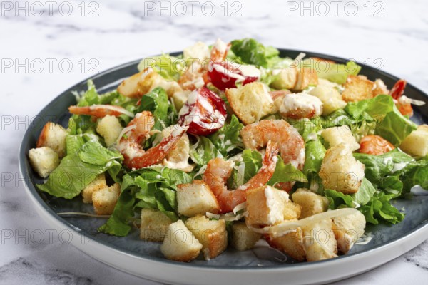 Caesar salad, with shrimp, on a marble background, top view, no people
