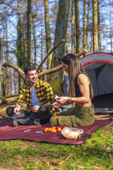 Hikers enjoying a game of cards while camping in the forest, sharing laughter and creating memories in the beauty of nature