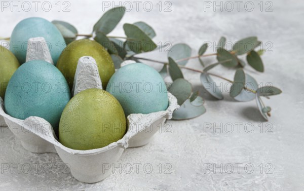 Easter colored eggs, in green and turquoise tones, with eucalyptus leaves, Easter card, top view, no people