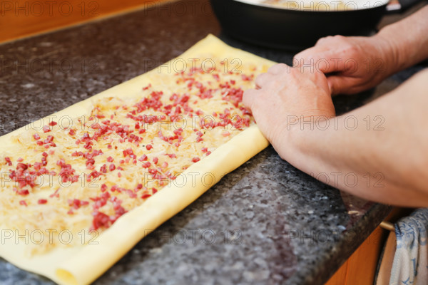 Swabian cuisine, preparation of Krautkrapfen, Swabian Mehlsäck, roll up raw pasta pancakes with sauerkraut and smoked meat, savoury, salty, main course, grandmother's cooking, regional, home cooking, typical Swabian, traditional cuisine reinterpreted, men's hands, food photography, studio, Germany, Europe