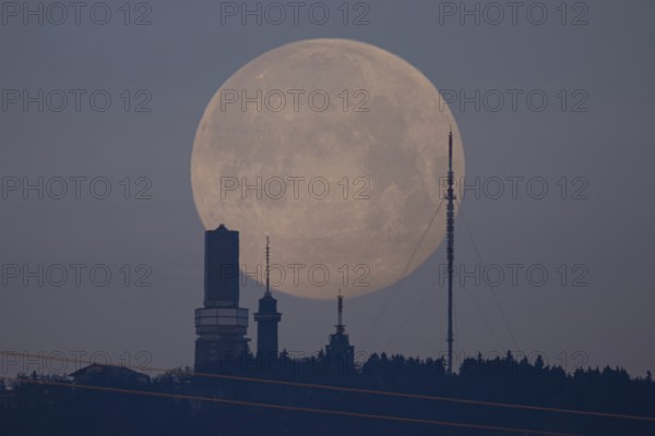 The first full moon of the year, also known as the wolf moon, disappears behind the Großer Feldberg im Taunus, Schmitten, Großer Feldberg im Taunus, Hesse, Germany, Europe