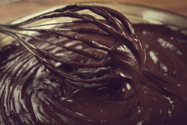 A bowl of chocolate dough, a whisk for whipping, baking, structure and consistency, homemade, top view, no people