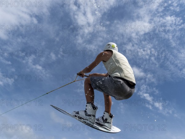 Young man jumping and flying with wakeboard, water sports and water skiing in the wakepark