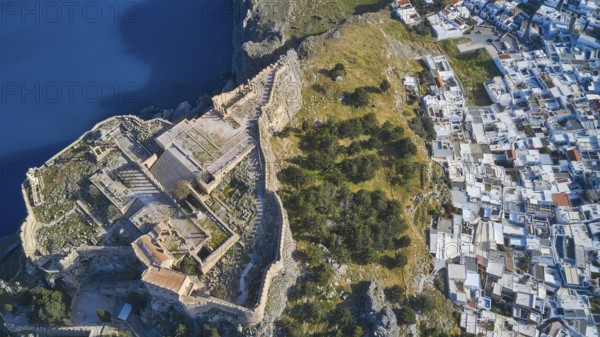 Drone shot, Acropolis of Lindos, late afternoon light, aerial view of an ancient fortress on the coast next to a white town of houses, archaeological site, Lindos, Rhodes, Dodecanese, Greek Islands, Greece, Europe
