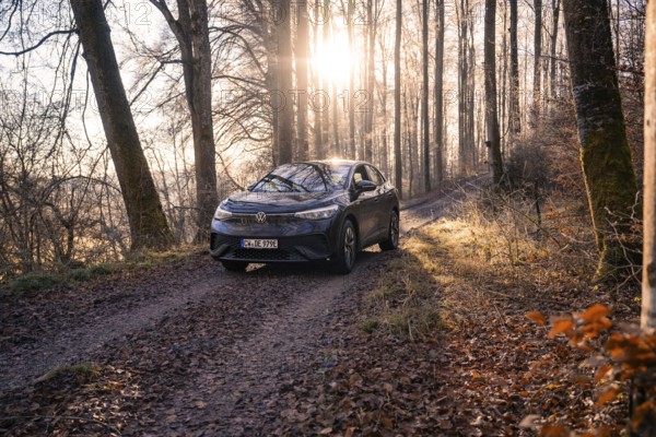 Vehicle on a forest path, illuminated by sunlight through the trees, car sharing, electric car, Volkswagen ID 5, Gechingen, Hecken und Gäu region, Black Forest, Germany, Europe