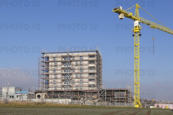 Incomplete building with yellow construction crane in clear sky, housing construction, new construction of 50 flats, new development area, apartment building, construction site, Winnenden, Baden-Württemberg, Germany, Europe