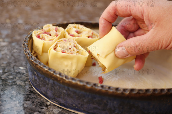 Swabian cuisine, preparation of Krautkrapfen, Swabian Mehlsäck, stuffed pasta pancakes with sauerkraut and smoked meat in a casserole dish, hearty, savoury, main course, raw pasta pancakes, grandmother's kitchen, regional, home cooking, typical Swabian, traditional cuisine reinterpreted, men's hands, food photography, studio, Germany, Europe