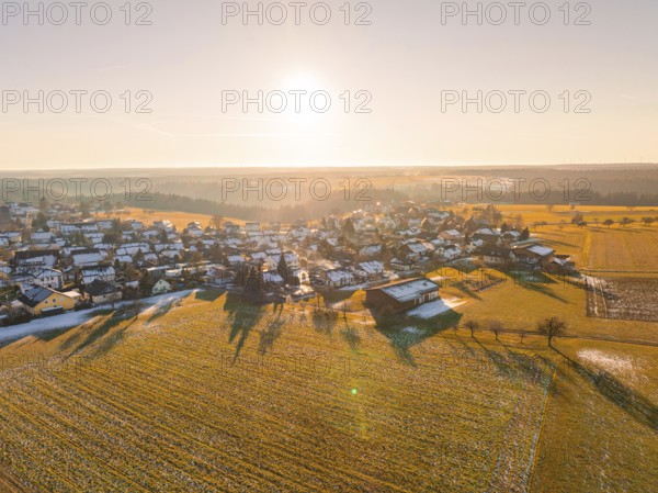A snowy village in the light of the sunrise with surrounding fields, Neuweiler, district of Calw, Black Forest, Germany, Europe