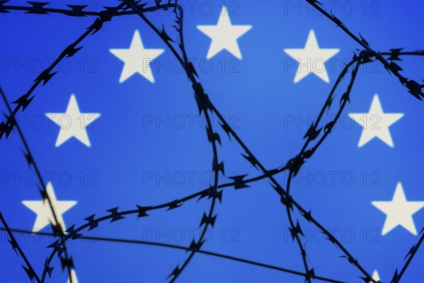 Symbolic image, migration, defence against refugees wanting to enter the EU, barbed wire overarches the stars of the EU flag against a blue sky, border, border fence