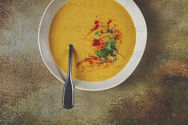 Pumpkin cream soup, in a white bowl on a textured background, top view, homemade, no people, rustic style