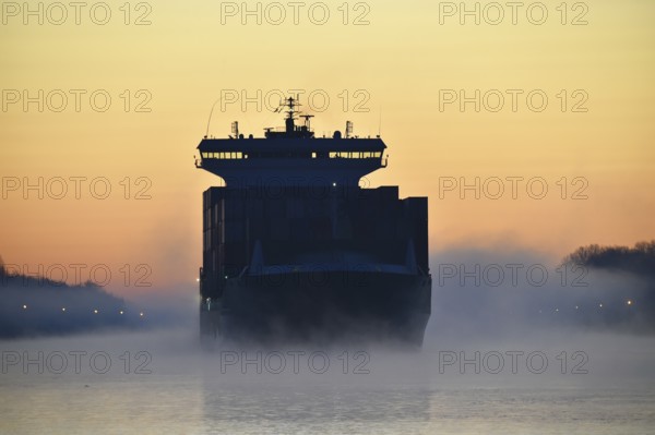 Container ship sailing at sunrise and fog in the Kiel Canal, NOK, Kielkanal, Kiel Canal, Schleswig-Holstein, Germany, Europe