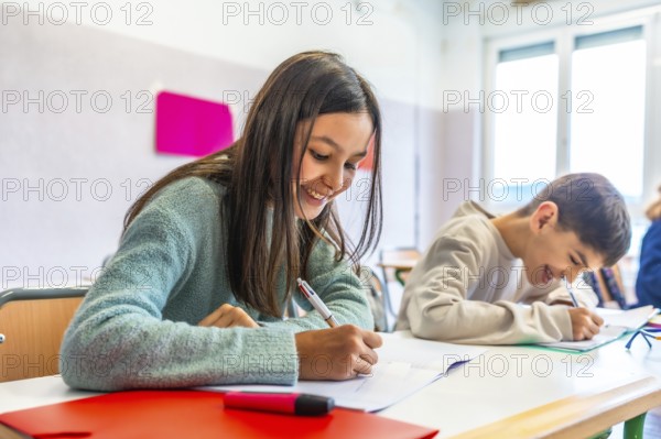 Happy elementary age children writing enthusiastically in notebooks during class, engaging with lessons and enjoying their school experience