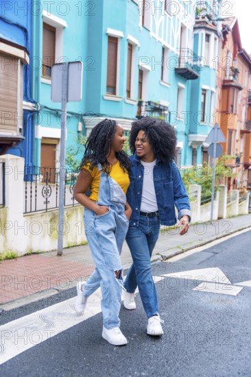 Vertical photo of a young african american couple walking together along a street with colorful facades