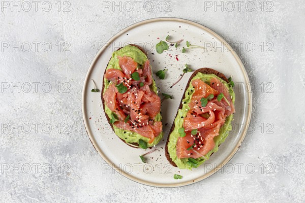 Breakfast, Sandwiches with smoked salmon and avocado, on dark rye bread, with microgreens, on a marble table, homemade, no people