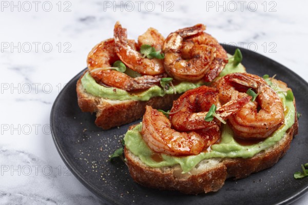 Sandwiches with avocado and caramelized shrimp, micro-greens, breakfast, on a plate, top view, homemade, no people