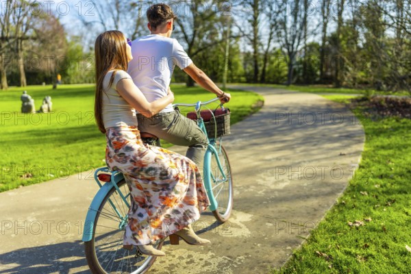 Romantic couple enjoying a leisurely bike ride through a sunny park, embracing the simple joys of life and love