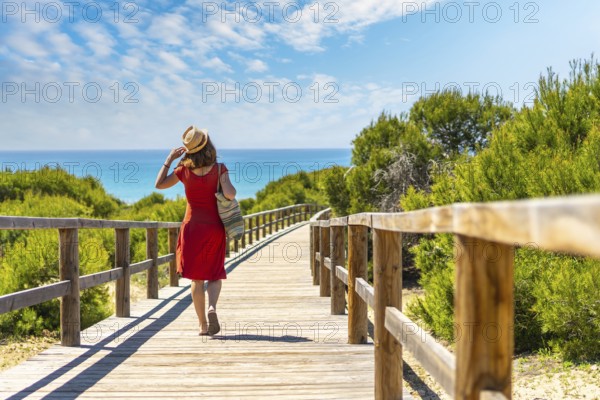 A young girl on the wooden path to Playa Moncayo in Guardamar del Segura next to Torrevieja, Alicante. Community of Valencia. Spain, holidays in the Mediterranean