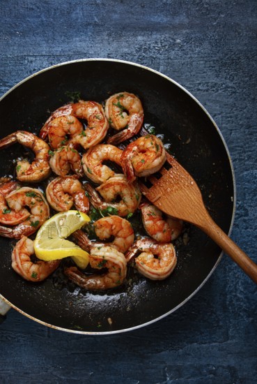 Fried tiger prawns, jumbo, in garlic sauce, in butter, with herbs, in a frying pan, homemade, no people