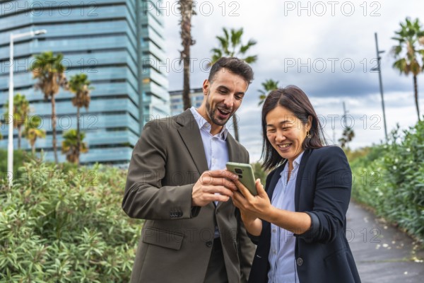 Relaxed and happy multi-ethnic female and male business colleagues using mobile phone at city
