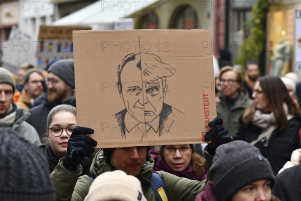 Heidelberg, Germany - February 12th 2025: Person holding up sign comparing CDU politian Friedrich Merz to USA president Donald Trump in crowd at protest against far-right