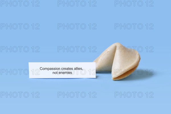 Fortune cookie with motivational text saying 'Compassion creates allies, not enemies on blue background