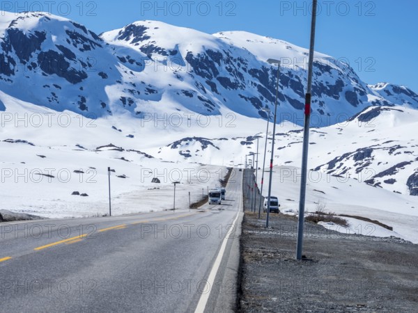 Camper vans driving through snowy high mountain landscape, Haukelivegen road, E134, Norway, Europe