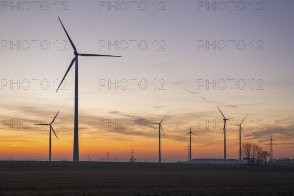 Wind turbines at sunset, colourful clouds and trees in the background, near Ulm, Swabian Alb, Baden-Württemberg, Germany, Europe