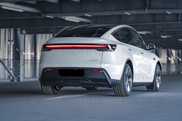 Rear of a modern electric car with eye-catching LED strip in a multi-storey car park, Tesla New Model Y Juniper, Calw, Germany, Europe
