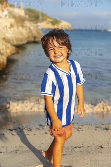 Happy child walking on the beach of s'amarador in mallorca, spain, enjoying summer holidays by the mediterranean sea