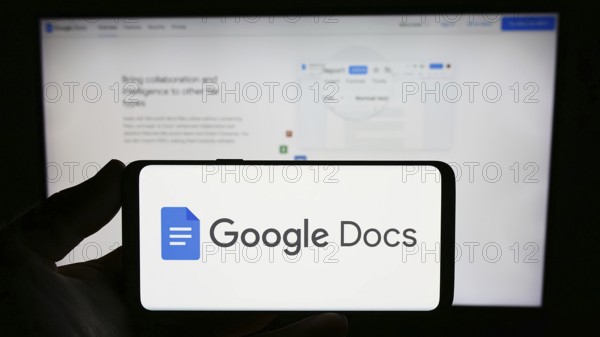 Stuttgart, Germany, 09-23-2023: Person holding smartphone with logo of online word processing product Google Docs on screen in front of website. Focus on phone display, Europe