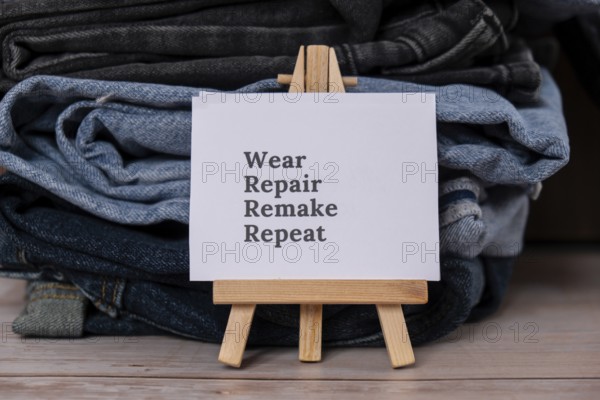 WEAR REPAIR REMAKE REPEAT text on paper note on Jeans clothes assortment Second hand sustainable shopping. Capsule minimal wardrobe. Sustainable fashion overconsumption, conscious buying consumption, slow fashion idea concept. Low-waste lifestyle