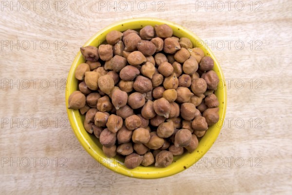 Flat Lay of Black Brown Chickpeas in a Yellow Bowl on Neutral Wooden Background, Top View