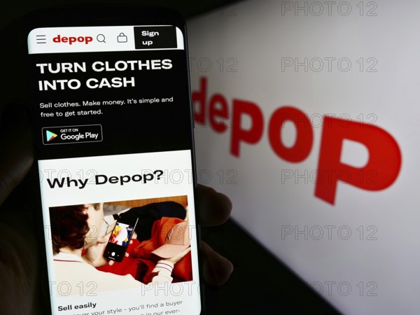 Stuttgart, Germany, 07-09-2023: Person holding mobile phone with web page of social e-commerce company Depop Limited on screen in front of logo. Focus on center of phone display, Europe