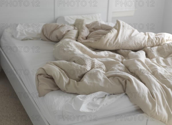 Unmade bed with ruffled blanket