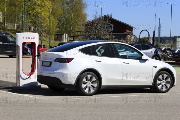 White Tesla Model Y AWD electric car charging battery at Tesla Supercharger station in Salo, Finland. May 11, 2024