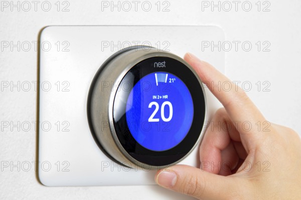 Calgary, Alberta, Canada. Jun 5, 2020. A person cooling down Home Air Conditioning, temperature is on centigrade celsius metrics using a Nest smart thermostat on a white wall