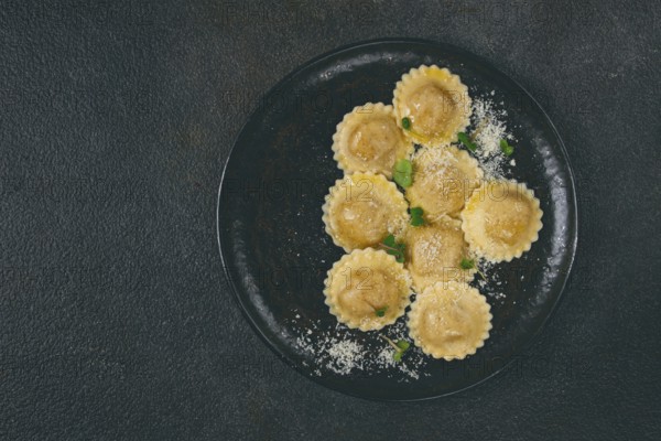 Fresh ravioli with cheese and microgreens, on a black plate, top view, no people