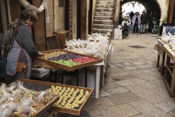 Bari, Italy, 27 November, 2023: woman pasta maker laying out her wares in the iconic Strada del Orecchiette in the old town of Bari Vecchio, Europe