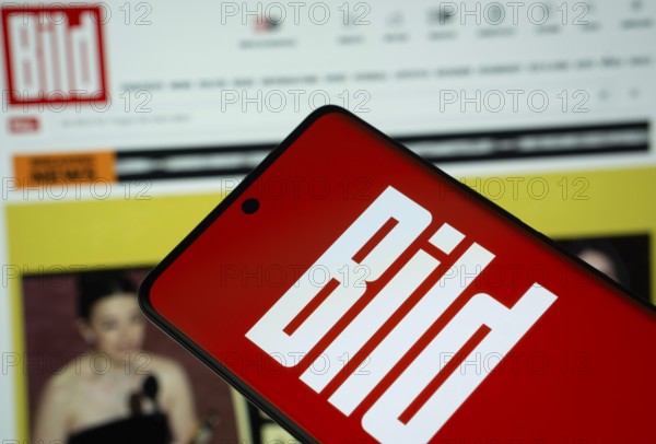 The logo of the German newspaper Bild is displayed on a smartphone screen, and the website bild.de is visible on a computer screen in the background