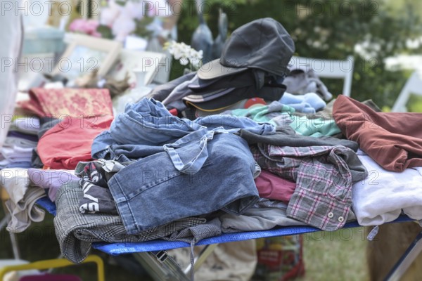 Used clothes and caps for sale at a flea market or garage market on a sunny weekend day, copy space, selected focus